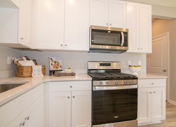 a white kitchen with black appliances and white cabinets at Jackson Run Townhomes, Whitestown, 46075