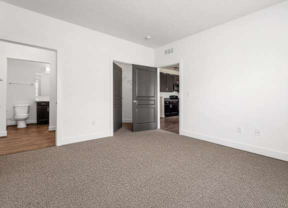A room with a carpeted floor and a doorway leading to a kitchen. at River View at Bexley Apartments, Ohio, 43209