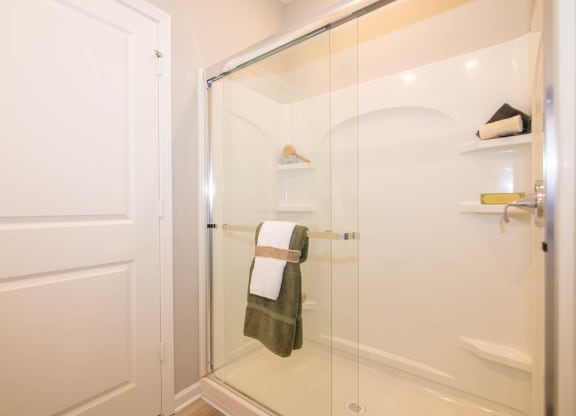 a bathroom with white tiles and a glass door at Jackson Run Townhomes, Whitestown Indiana