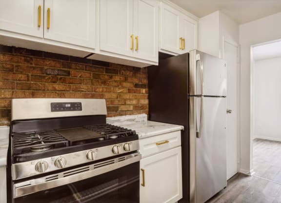 a kitchen with white cabinets and a brick wall