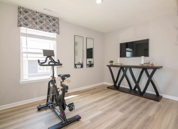 a home gym with a exercise bike in front of a window at Jackson Run Townhomes, Whitestown
