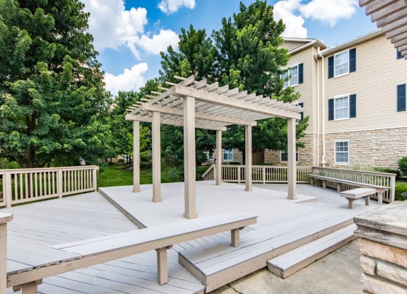 a picnic area with benches and a pergola on a deck
