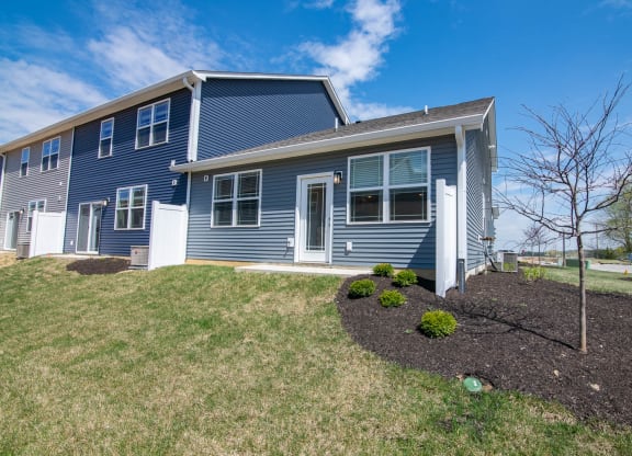 the front of a blue house with a lawn and shrubs at Jackson Run Townhomes, Whitestown, 46075