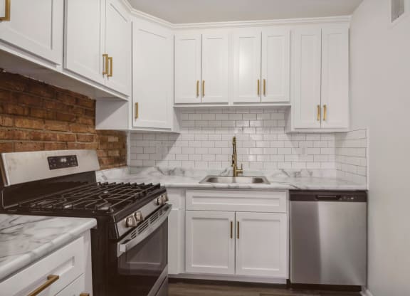 a kitchen with white cabinets and a brick wall