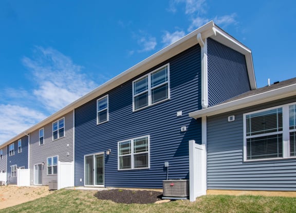 a blue house with white windows on a sunny day at Jackson Run Townhomes, Whitestown Indiana