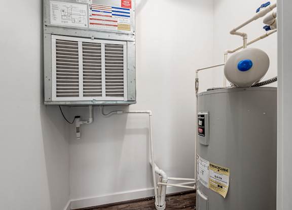 A room with a wall-mounted air conditioning unit and a tank on top of a cabinet. at River View at Bexley Apartments, River View at Bexley, Ohio