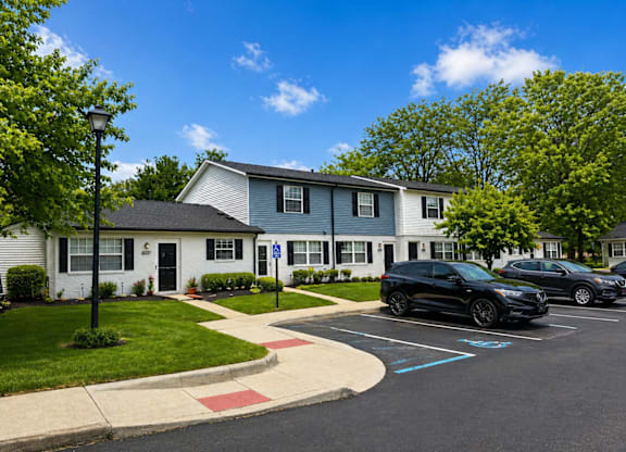 A sunny day at a residential area with a house, cars and a street light.