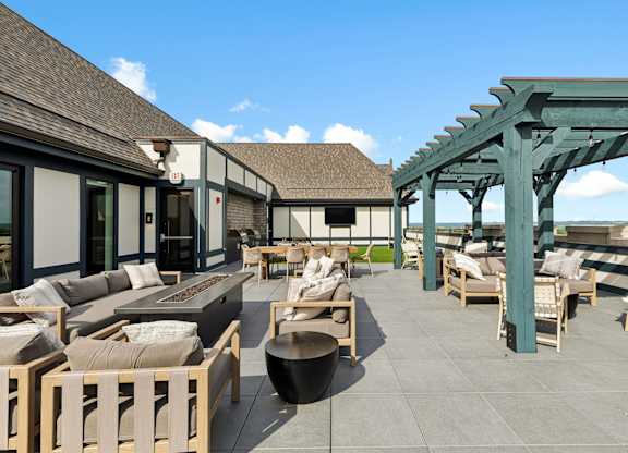 A patio with wooden furniture and a green pergola.