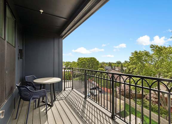 A balcony with a table and chairs overlooking a street.