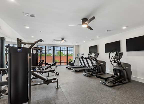 A gym with treadmills, elliptical machines, and a weight machine.