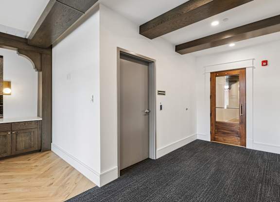 A hallway with a wooden floor and a white wall.