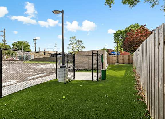 A green lawn with a fence and a lamp post.