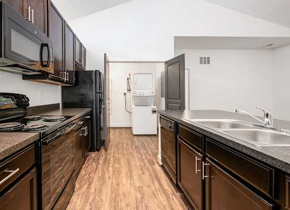 A kitchen with dark wood cabinets and black appliances. at River View at Bexley Apartments, River View at Bexley, OH