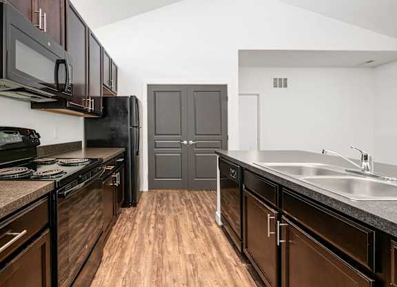 A kitchen with dark wood cabinets and a black stove top oven. at River View at Bexley Apartments, River View at Bexley 43209