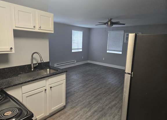 A kitchen with a black countertop and white cabinets.