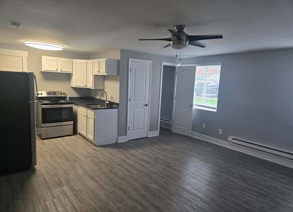 A kitchen with a black refrigerator and a fan on the ceiling.