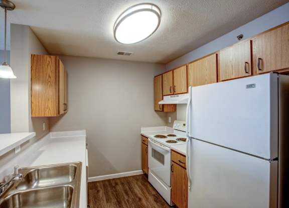 A kitchen with white appliances and wooden cabinets.