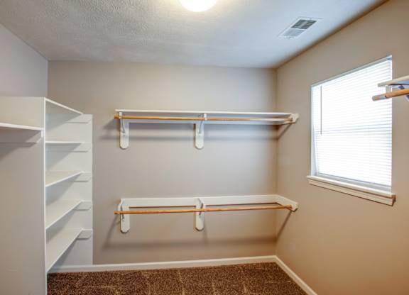 A room with a white shelving unit and a brown carpet.