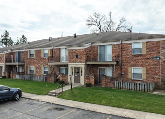 A brick apartment building with a car parked in front.