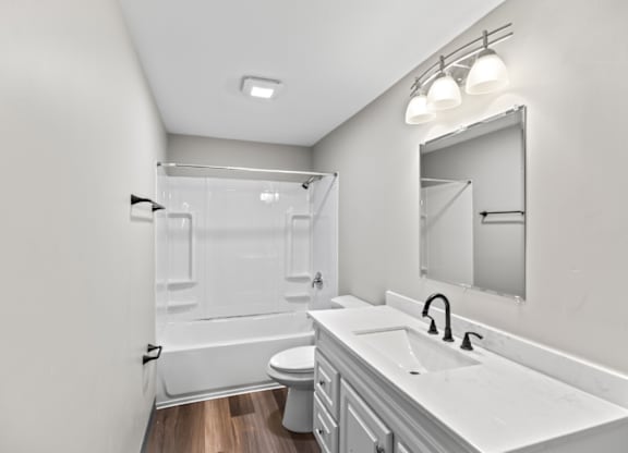 A white bathroom with a toilet, sink, and mirror.