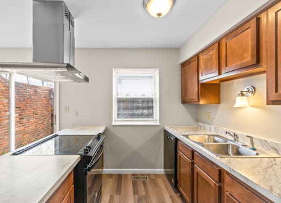 A kitchen with wooden cabinets and a brick wall.