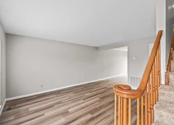 A room with wooden flooring and a staircase with wooden railings.