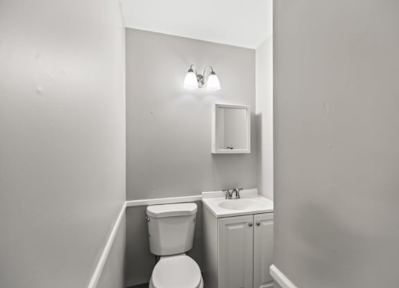 A bathroom with a toilet, sink, and medicine cabinet.