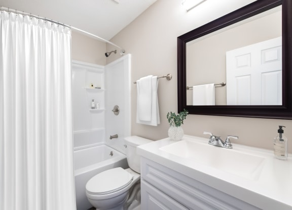 a bathroom with a white shower curtain and a white toilet next to a white sink with a