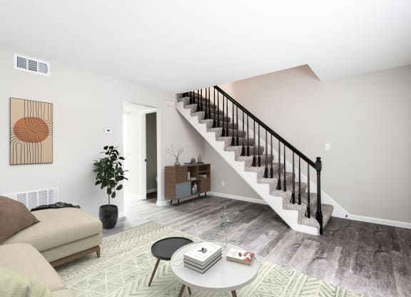 a living room with a staircase in the background and a couch and coffee table in the foreground