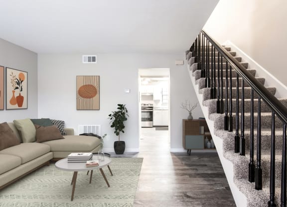 a living room with a staircase in the background and a couch and coffee table in the foreground