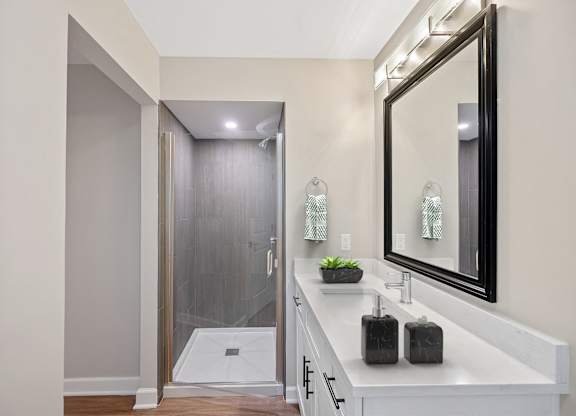 a white bathroom with a large mirror and a shower at Indian Creek Apartments, Cincinnati, OH
