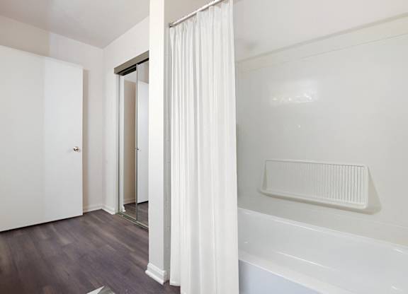 A white bathroom with a tub and a window.