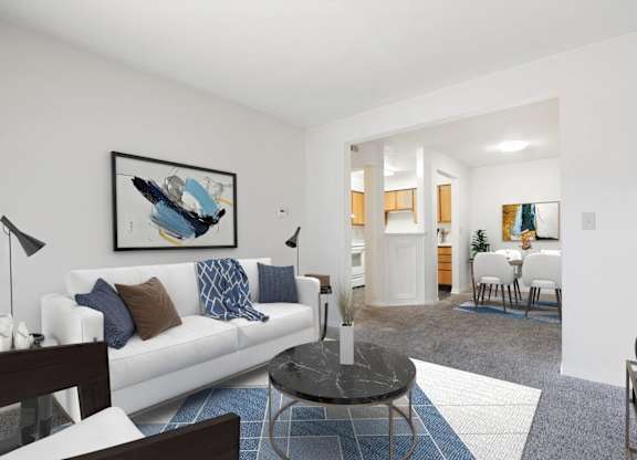A living room with a white couch and a blue and white rug.
