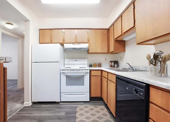 A kitchen with a white fridge and black dishwasher.