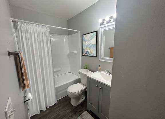A small bathroom with a toilet, sink, and shower.