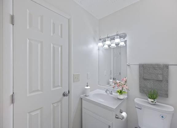 A white bathroom with a toilet, sink, and mirror.