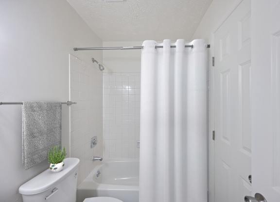 A white bathroom with a toilet, sink, and shower.