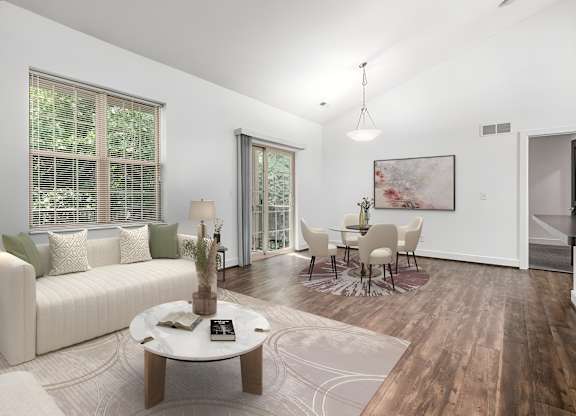 A living room with a white sofa, a coffee table, and a painting on the wall. at River View at Bexley Apartments, Ohio