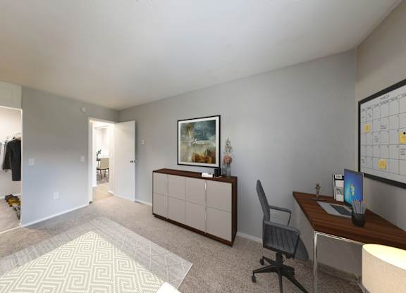 A room with a desk, chair, and a painting on the wall.