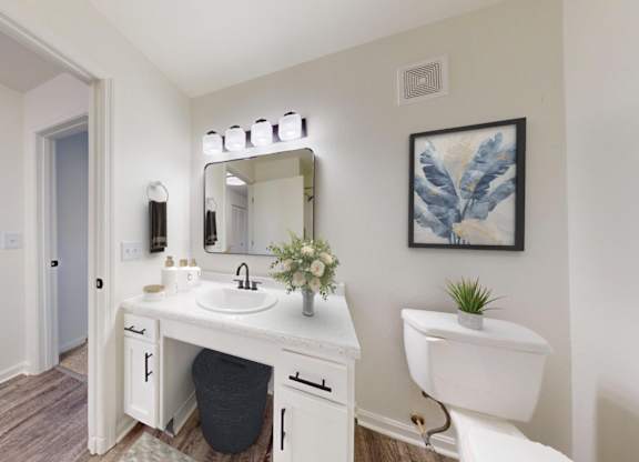 A white bathroom vanity with a mirror and lights above it.