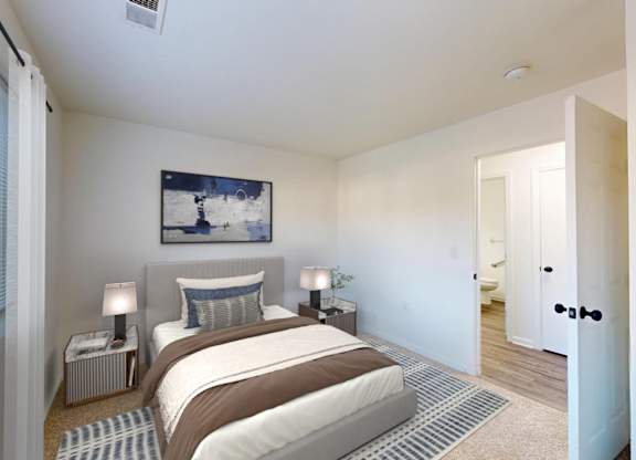 A bedroom with a bed, two lamps, and a painting on the wall.