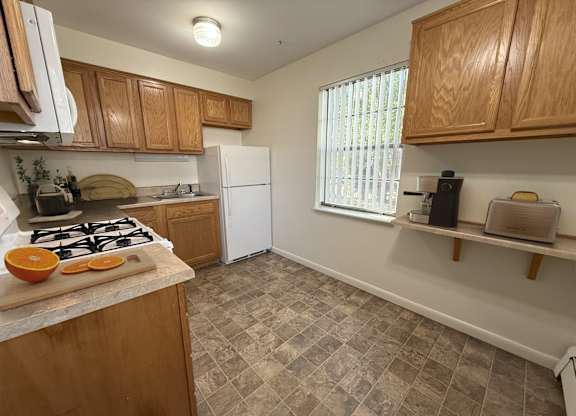 A kitchen with a white refrigerator and wooden cabinets.