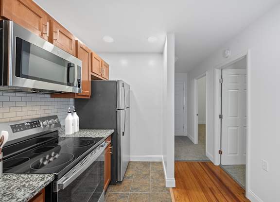 A kitchen with a black refrigerator and stove top oven.
