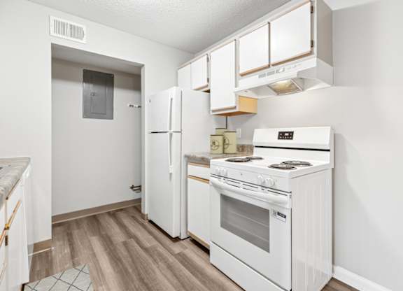 A white kitchen with a refrigerator, oven, and cabinets.