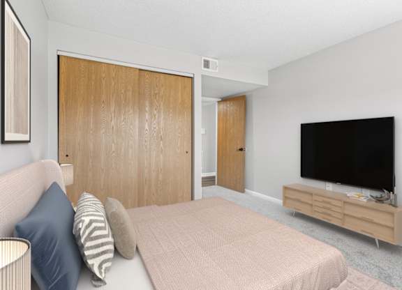 A bedroom with a bed, a couch, and a television.