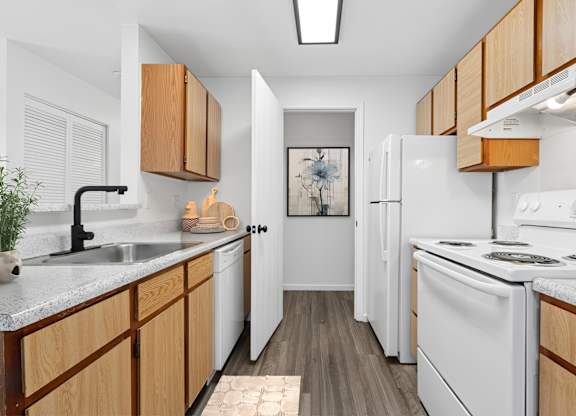 A kitchen with white appliances and wooden cabinets.