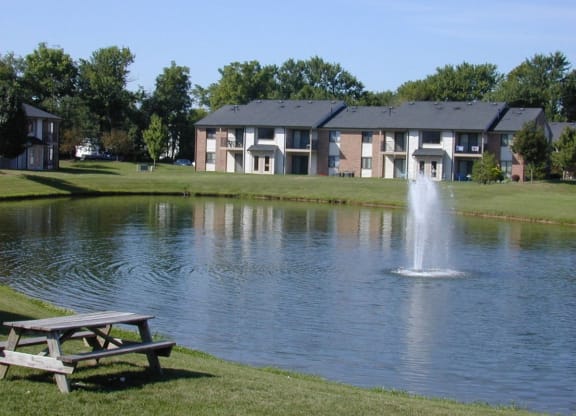 a pond with a fountain in front of a building