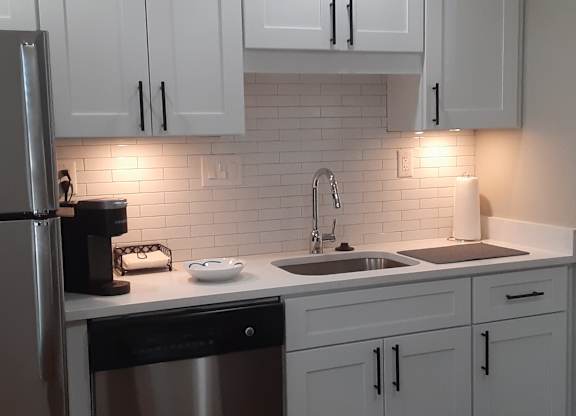 A kitchen with white cabinets and a stainless steel refrigerator.