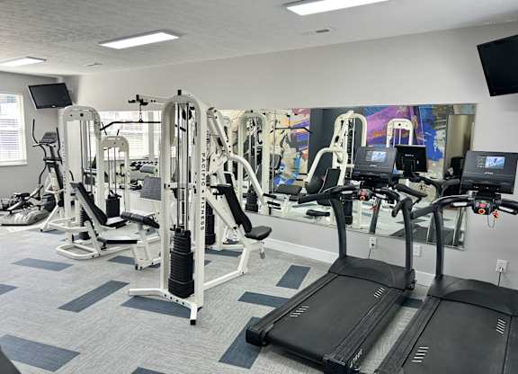A gym with treadmills, weight machines, and exercise equipment.
