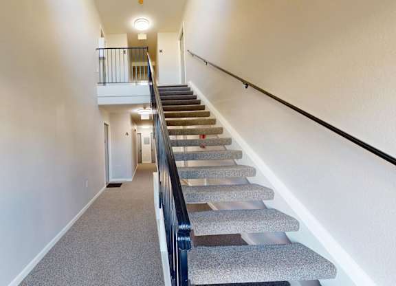 A staircase with a carpeted runner and a black handrail.